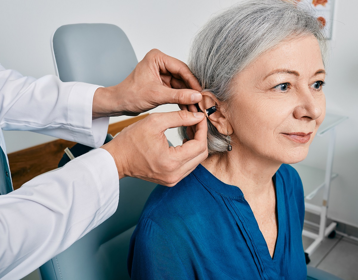Senior Woman During Installation Hearing Aid Into Her Ear By Her
